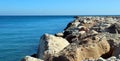 Breakwater of large stones in blue sea to horizon, road to sea, beautiful seascape, Mediterranean beaches Royalty Free Stock Photo