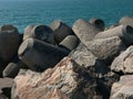 Breakwater made of boulders, rocks and moulded concrete with blue ocean water in background