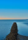 Breakwater made of gravel stones in the blue North Sea against a blue sky, abstract, calm, meditative