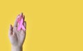 Breast Cancer Awareness. Hand of woman holding pink ribbon on yellow background. World cancer day Royalty Free Stock Photo