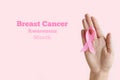 Breast Cancer Awareness Month. Woman hand holding pink ribbon on pink background. International symbol of Breast Cancer Royalty Free Stock Photo