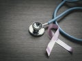 Breast cancer awareness pink ribbon with doctor stethoscope on wooden background, october symbol, healthcare and medicine concept Royalty Free Stock Photo