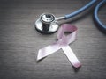 Breast cancer awareness pink ribbon with doctor stethoscope on wooden background, october symbol, healthcare and medicine concept Royalty Free Stock Photo