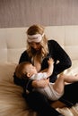 Breast feeding: Young blonde mother breastfeeds her baby boy child in bedroom wearing black sleeping robe costume - Son Royalty Free Stock Photo