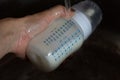 Breast milk in the bottle thawing under running water