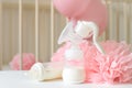 Breast pump and baby bottles with milk, various festive paper decor and balloons in front of baby bedroom. Royalty Free Stock Photo