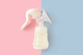 Breast pump bottle of milk for newborn baby over pink and blue pastel colors background. Maternity and baby care concept. Girl or Royalty Free Stock Photo