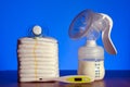 Breast pump and nappies and thermometer with a pacifier on a blue background