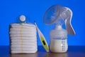 Breast pump and nappies and thermometer with a pacifier on a blue background