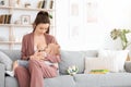 Breastfeeding Concept. Young woman lactating her toddler baby on couch at home