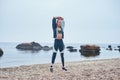 Breathe deep. Strong disabled athlete woman with prosthetic leg doing stretching exercises while standing at the beach