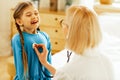 Girl taking a breath while a pediatrician checking her lungs.