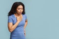 Breathing problem. Sick black woman with chest pain touching inflammated zone over blue background with free space