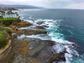 Breathtaking aerial shot of the deep green ocean water, the beach, the rocks, the palm trees and homes on the beach Royalty Free Stock Photo