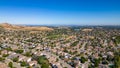 A breathtaking aerial view of Antioch, California: houses nestled amidst verdant hills, crisscrossed by meandering streets, all