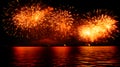 fireworks display illuminates the night sky, casting a fiery glow over calm waters near a distant cityscape