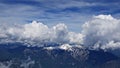 Breathtaking high angle shot of snowy mountains under the clouds and the sky in the background