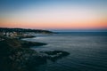 Breathtaking high angle shot of a town on the shore at the sea and the colorful sunset sky behind