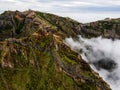 Breathtaking hiking trail with a view of a beautiful mountain landscape above the clouds of Madeira Island - Green Royalty Free Stock Photo