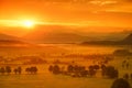 Breathtaking morning lansdcape of small bavarian village covered in fog. Scenic view of Bavarian Alps at sunrise with majestic mou Royalty Free Stock Photo