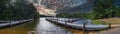 A breathtaking panoramic shot of the rippling waters of the lake with a long gray wooden dock over the water