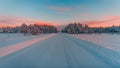 Breathtaking road covered with snow surrounded by trees under the colorful sky in Norway