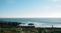 Breathtaking shot of a person enjoying the beauty of the ocean in a rocky coastline