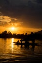 Breathtaking shot of a small boat's and some people's silhouettes on a beautiful sunset background Royalty Free Stock Photo