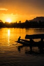 Breathtaking shot of a small boat's and some people's silhouettes on a beautiful sunset background Royalty Free Stock Photo