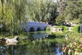 A breathtaking shot of a a stone bridge over a like with deep green lake water and lush green trees reflecting off the lake with b Royalty Free Stock Photo