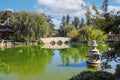 A breathtaking shot of a a stone bridge over a like with deep green lake water and lush green trees reflecting off the lake Royalty Free Stock Photo