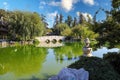 A breathtaking shot of a a stone bridge over a like with deep green lake water and lush green trees reflecting off the lake Royalty Free Stock Photo