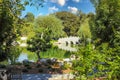 A breathtaking shot of a a stone bridge over a like with deep green lake water and lush green trees reflecting off the lake Royalty Free Stock Photo