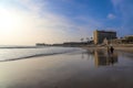 A breathtaking shot of the vast blue ocean water with waves rolling in to the silky smooth sands of the beach with people walking Royalty Free Stock Photo