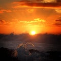 Breathtaking shot of waterdrops of the ocean and the orange sky during sunset in the background