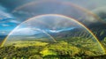 The breathtaking sight of a double rainbow stretching across a lush green valley.