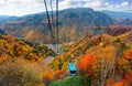 A breathtaking view from a cable car of Kurodake Ropeway flying over colorful autumn forests on the mountainside in Sounkyo Gorge