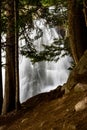 Breathtaking view of a majestic waterfall cascading down a rugged cliff with trees in the foreground Royalty Free Stock Photo