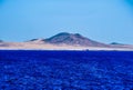 Breathtaking view of a mountain behind the beautiful calm ocean under the clear blue sky Royalty Free Stock Photo