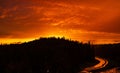 Breathtaking view of red cloudy sunset sky over silhouettes of treetops on a hill Royalty Free Stock Photo