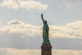 Breathtaking view of Statue of Liberty on Liberty Island in New York set against backdrop of pale blue sky with white clouds Royalty Free Stock Photo