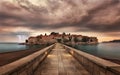 view of a tailed floor bridge leads to water under mountains at sunset Kotor Bay, Montenegro