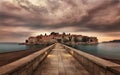 view of a tailed floor bridge leads to water under mountains at sunset Kotor Bay, Montenegro