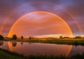 A stunning double rainbow arches over a serene landscape with a tranquil lake at sunset Royalty Free Stock Photo