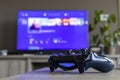 BRECHT, BELGIUM Ã¢â¬â MARCH 28 2019; A portrait of a PS4 controller, which is turned on, in front of a television.