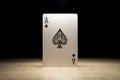 Brecht, Belgium - 29 may 2020: A portrait of the ace of spades standing up in the spotlight on a wooden table surrounded in