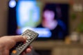 Brecht, Belgium - November 14 2019: A hand holding a television remote control with in the background a tv displaying a blurred