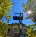 City worker standing in the Genie aerial lift installing Christmas lights