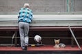 Bremen, Germany - June 19th, 2018 - Old man in checkered shirt leaning on a handrail with his back towards the camera with his lit