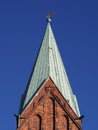 Bremen, Germany - Spire of St. Martini church with red brick walls, green copper roof, weather vane and blue sky in the background Royalty Free Stock Photo